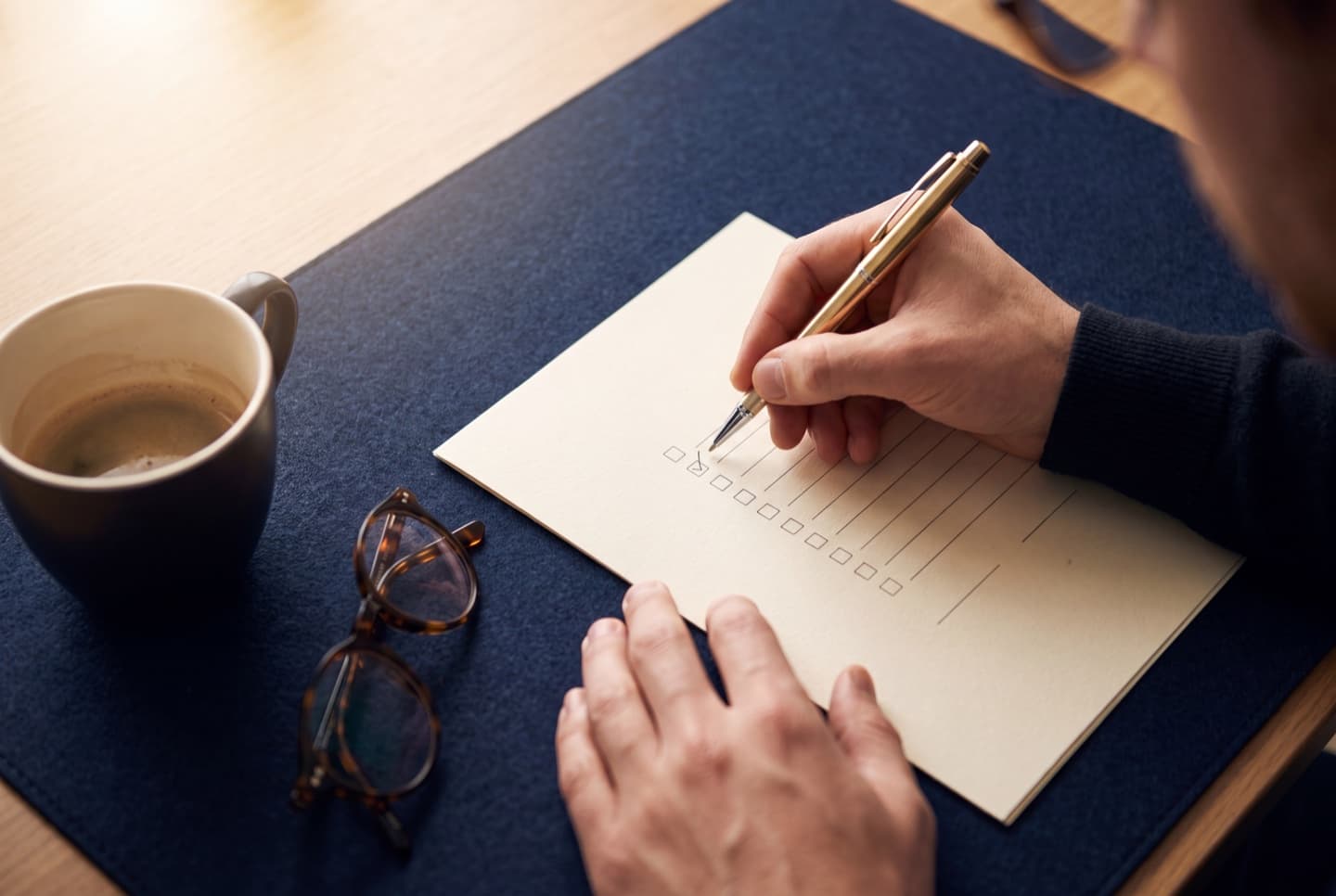 Hands reviewing a printed checklist with a gold pen on a dark navy desk, representing the required contents of a GDPR privacy policy